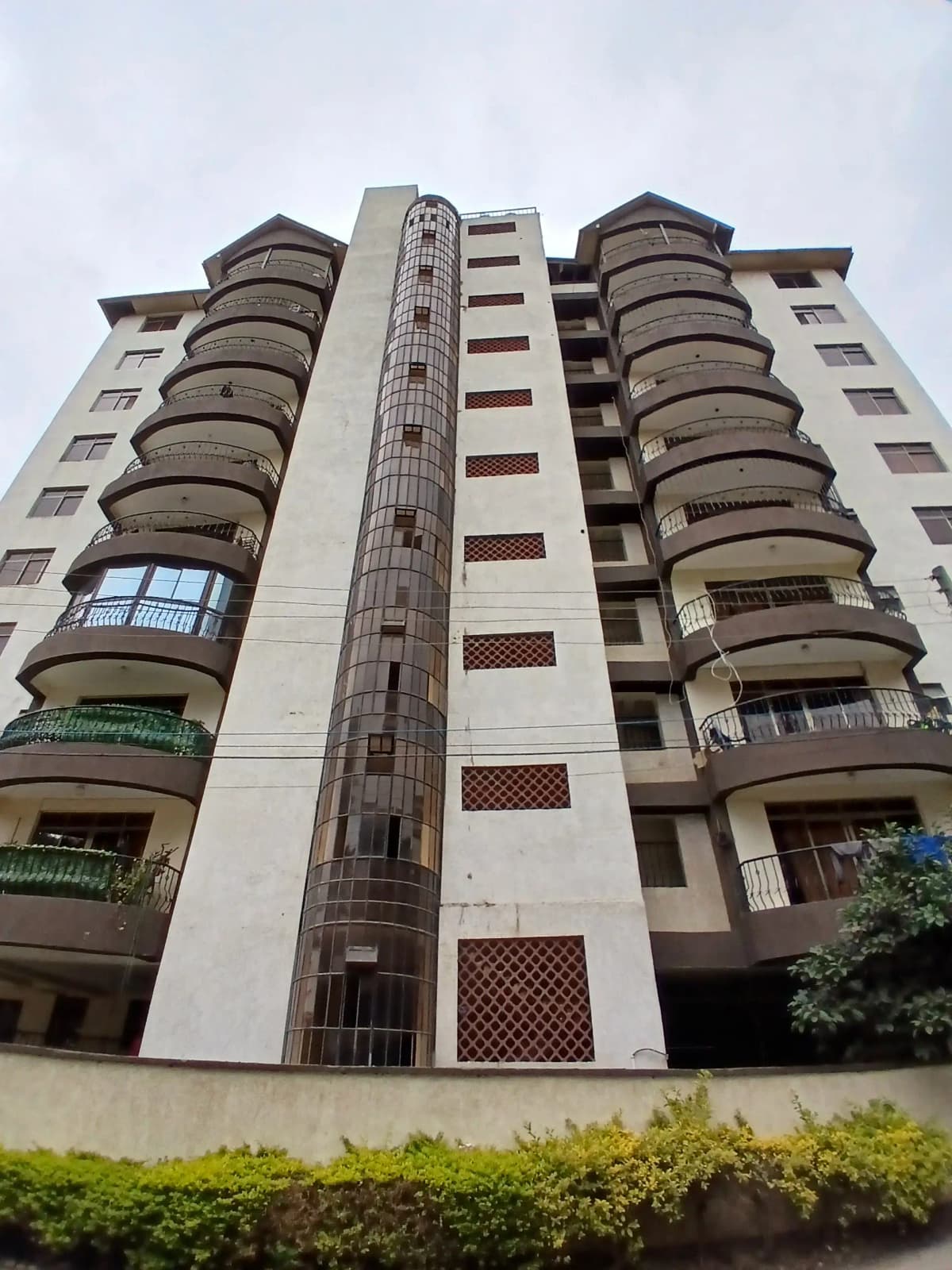 Modern apartment building facade with curved balconies and green landscaping
