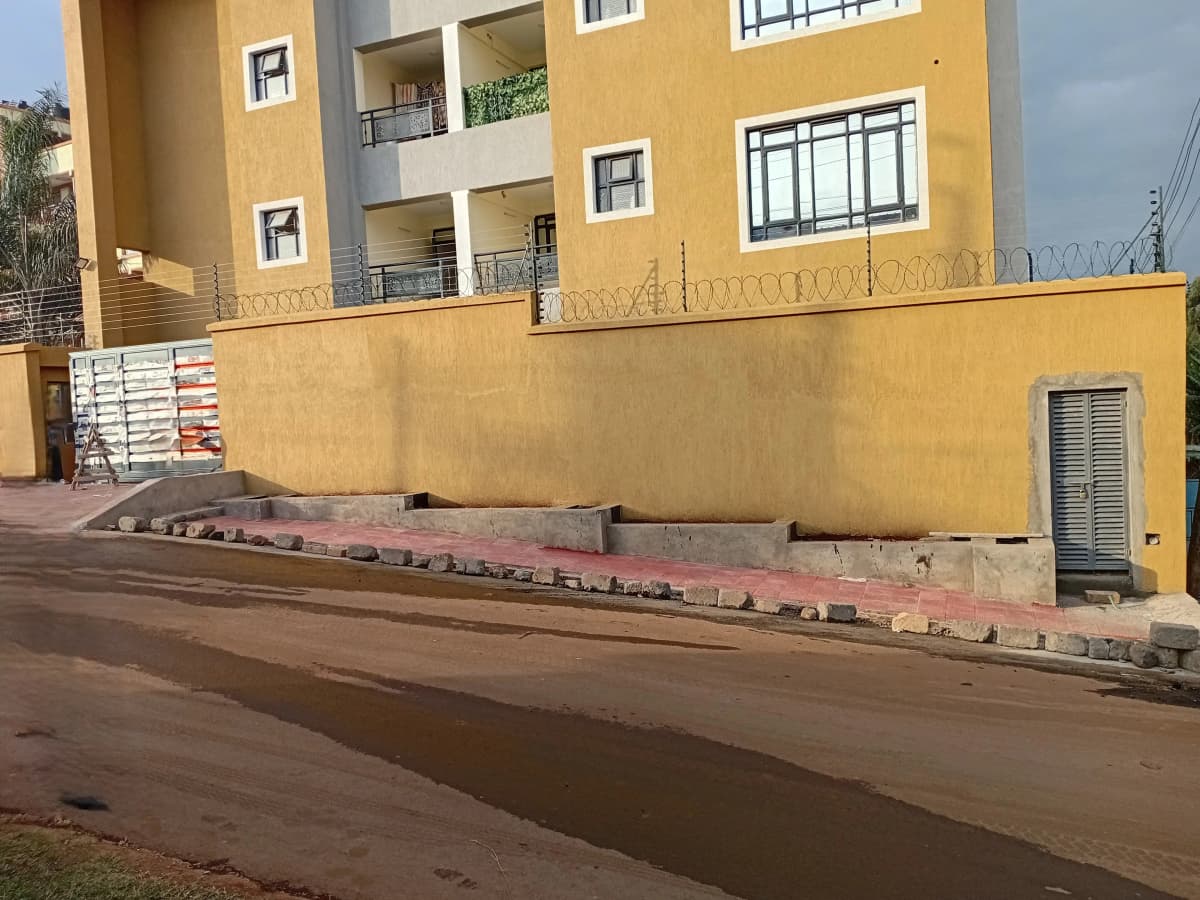 Yellow apartment building facade with gated compound entrance