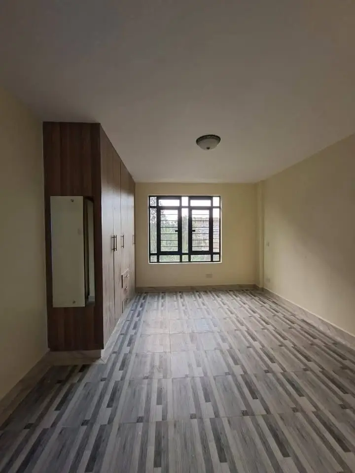 Unfurnished bedroom with wooden wardrobe and natural light