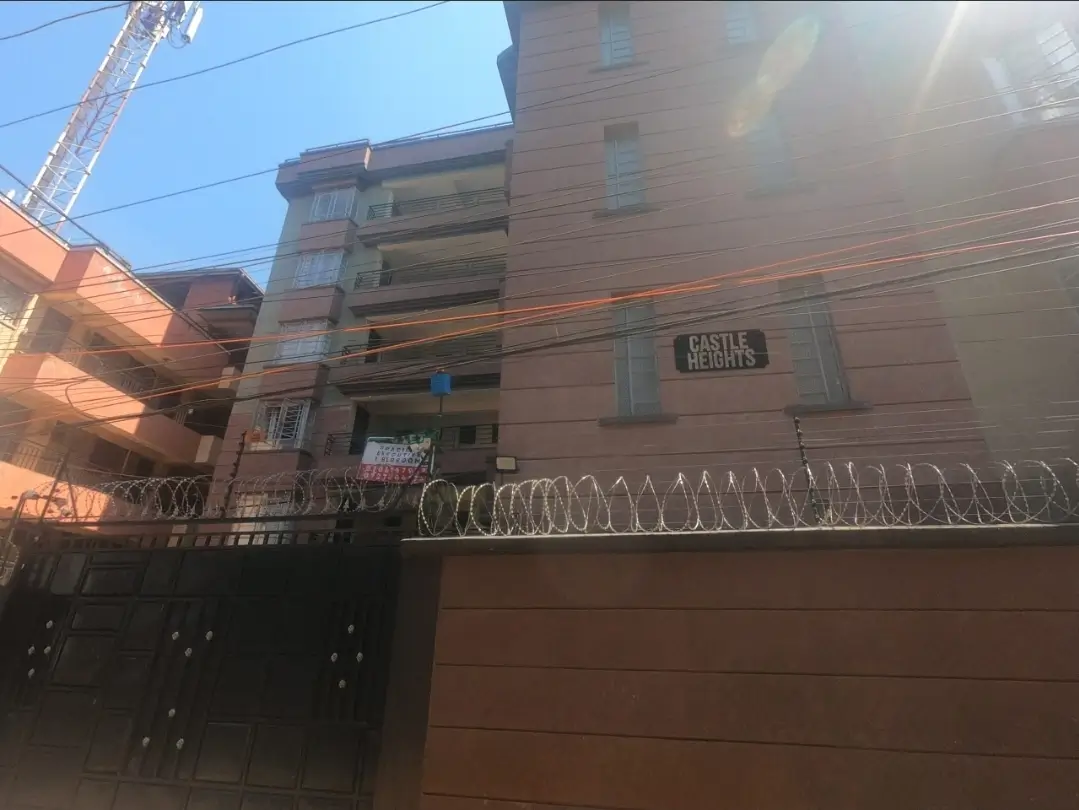 Multi-story residential building facade with security wall and gate