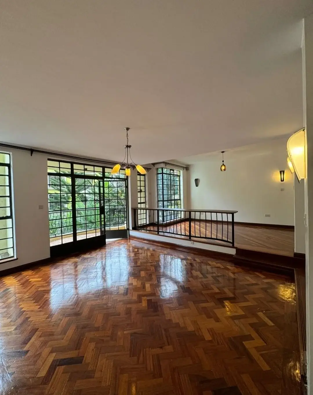 Spacious living room with herringbone wood floors and balcony access