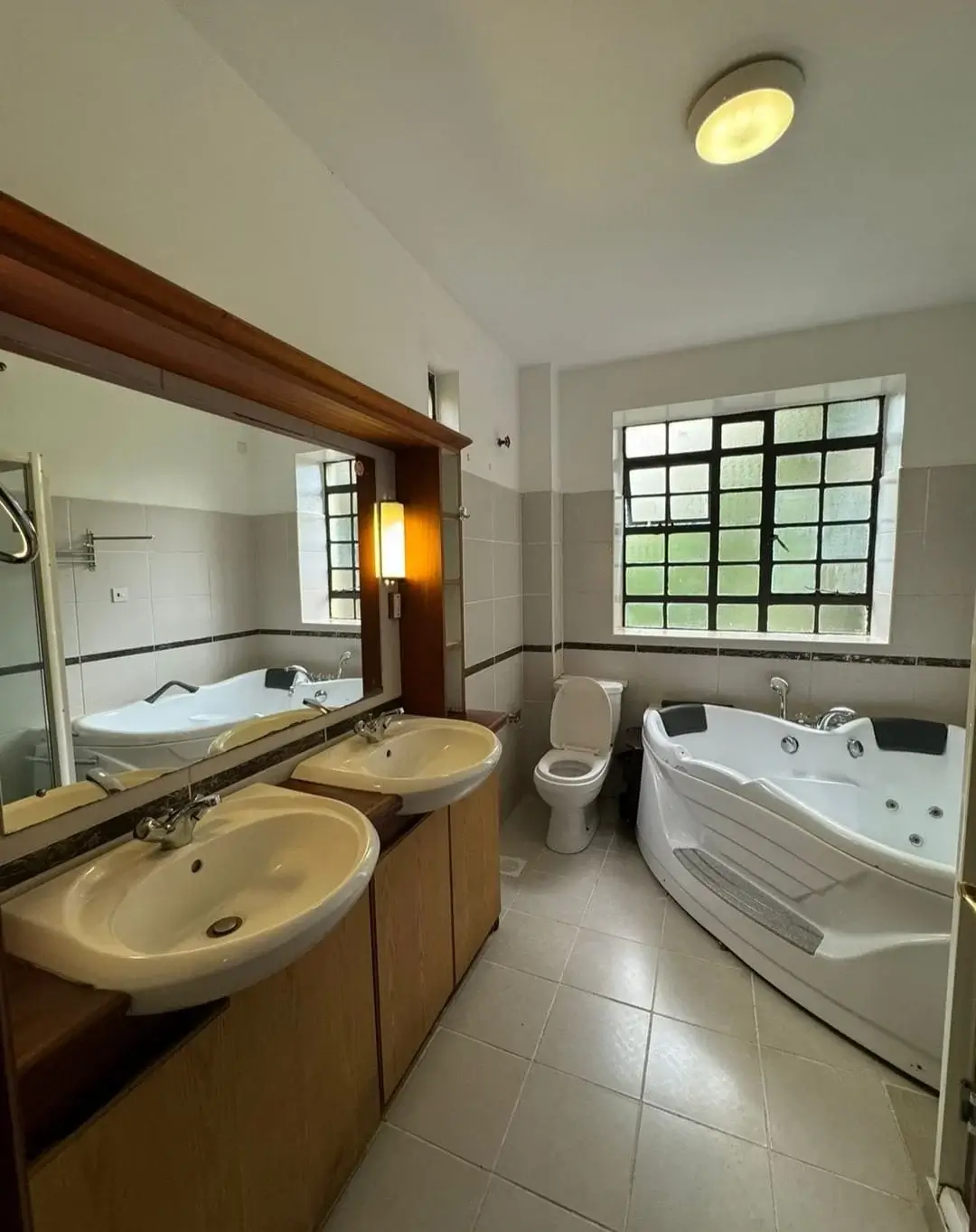 Spacious bathroom with dual sinks, jacuzzi tub, and large window