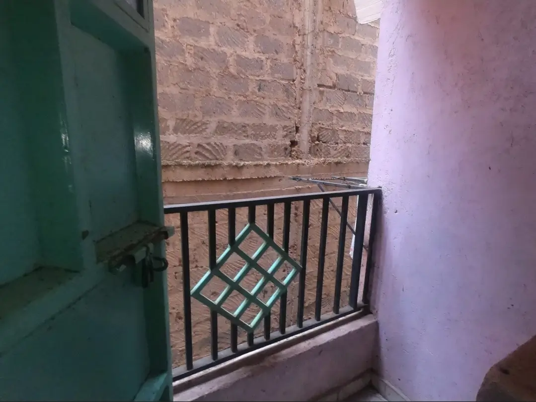 Small balcony with black metal railing and brick wall
