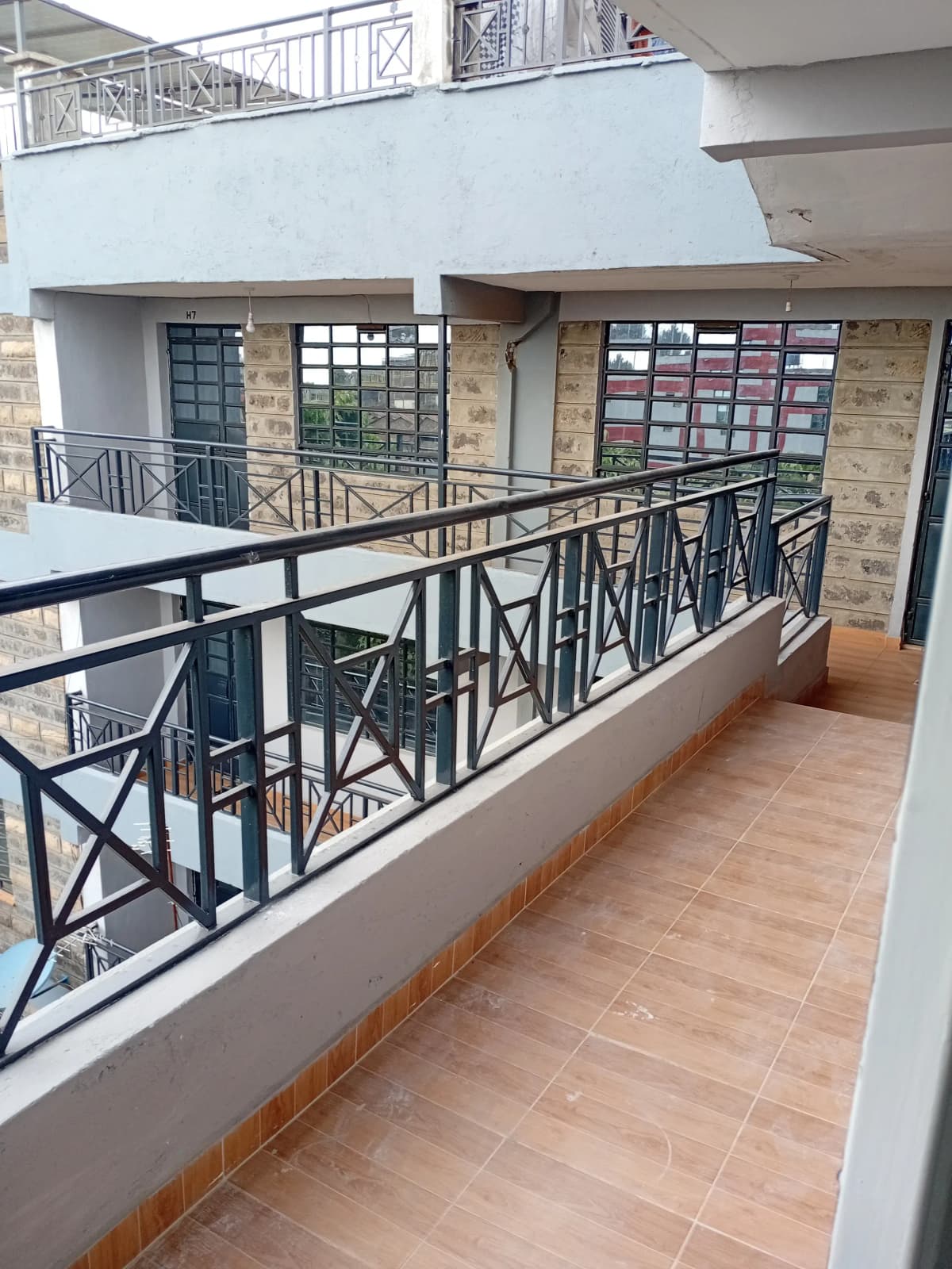 Spacious balcony with black metal railings and terracotta tiles
