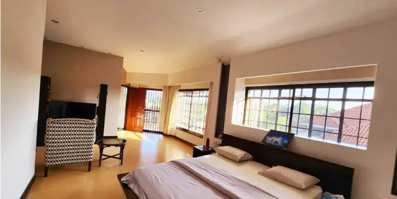 Spacious master bedroom with large windows and open lounge area