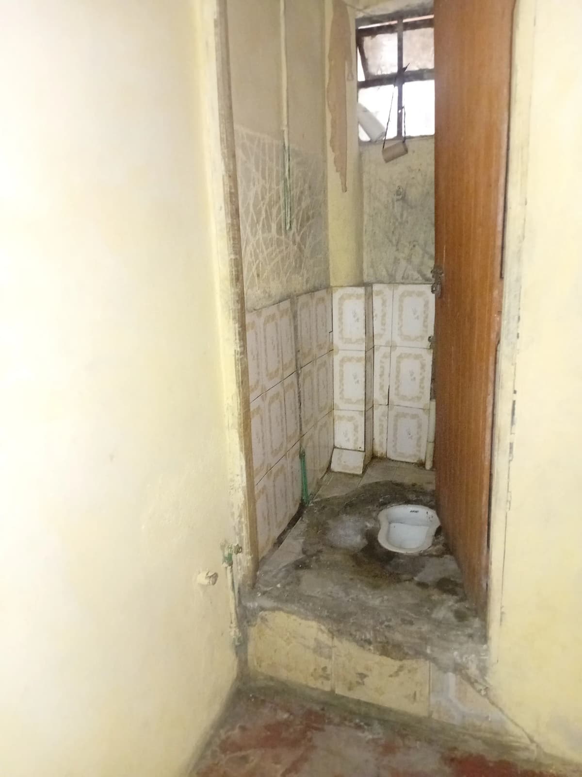 Narrow bathroom with tiled walls and basic fixtures