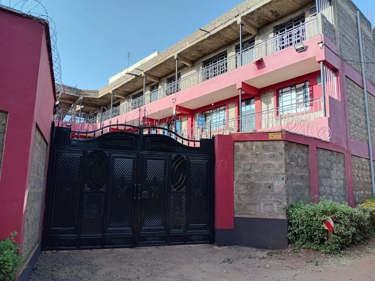 Modern multi-story residential building with pink and red facade