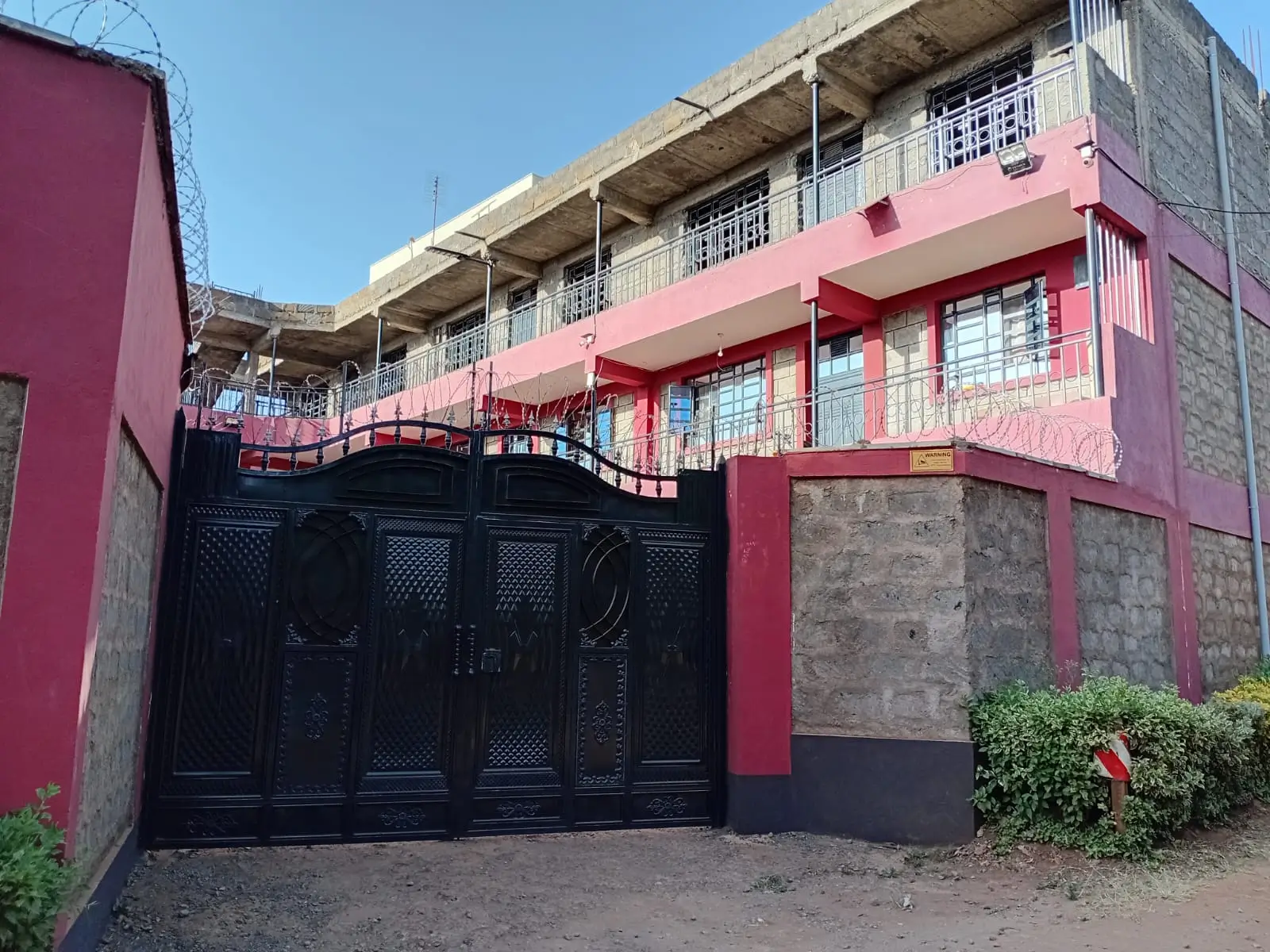 Modern multi-story residential building with pink and red facade