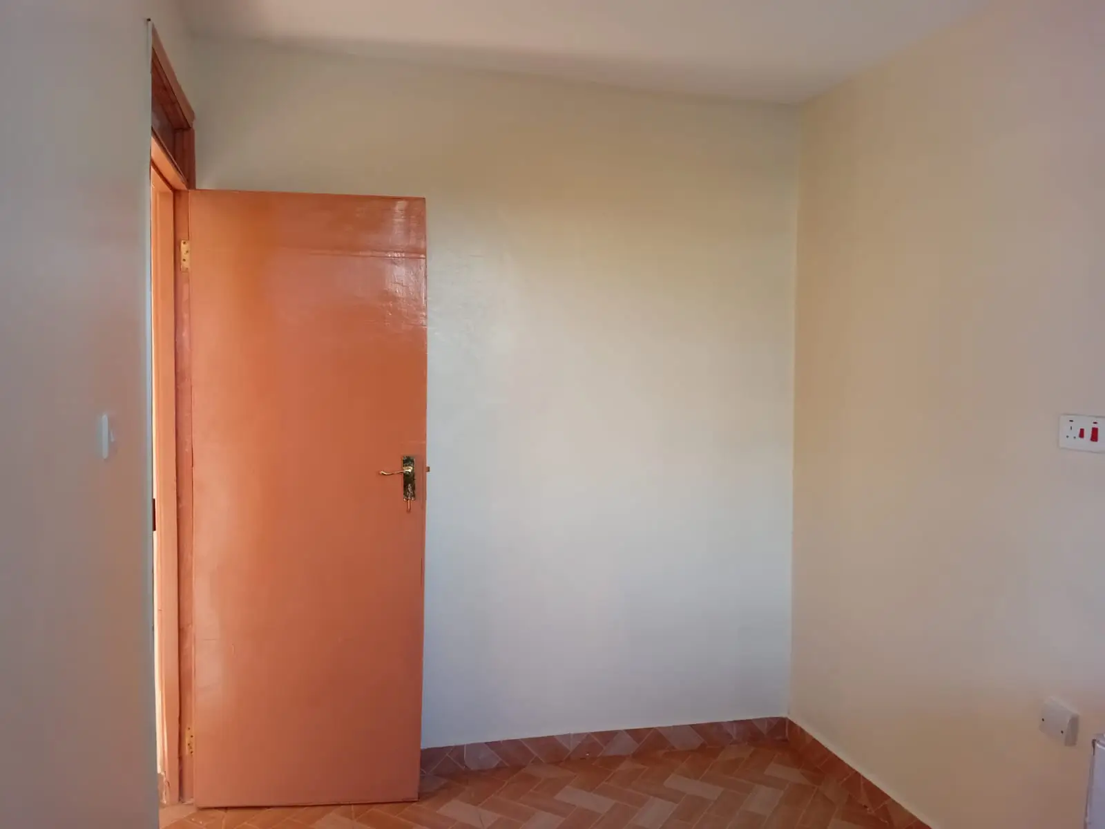 Empty bedroom with orange door and wooden floor