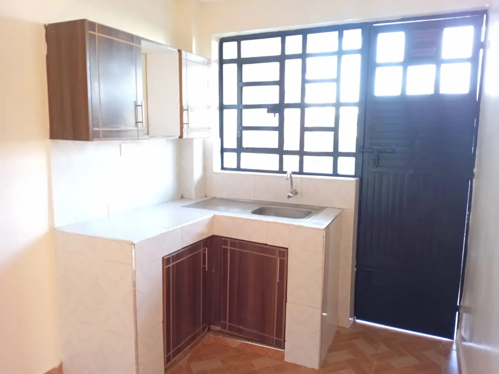 Compact kitchen with sink, cabinet storage, and window