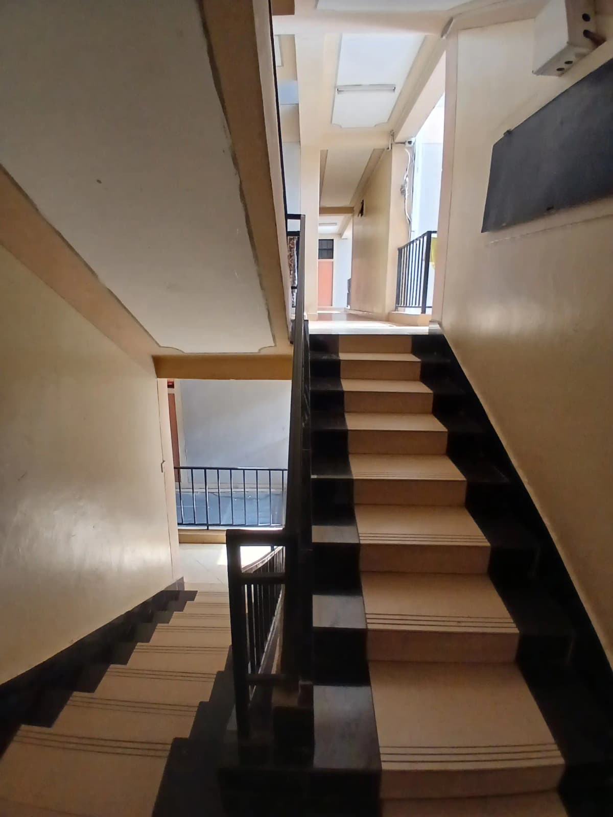 Interior staircase with black railing and wooden steps