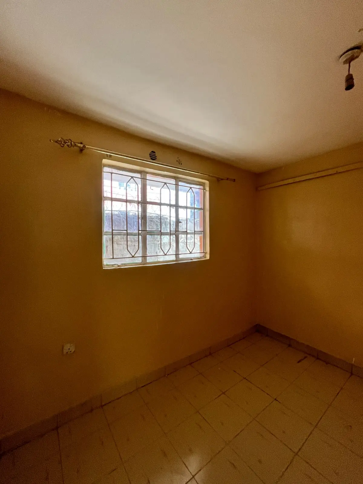 Unfurnished bedroom with yellow walls and barred window
