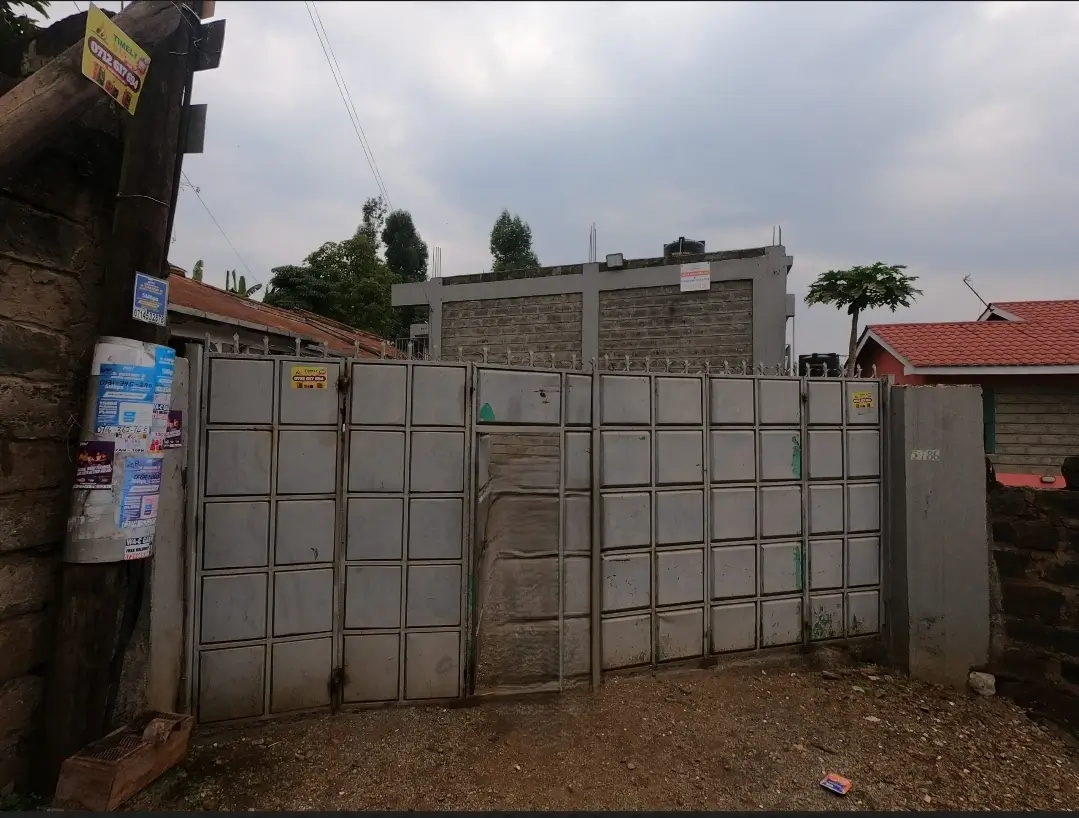 Metal gate entrance with compound walls and residential building