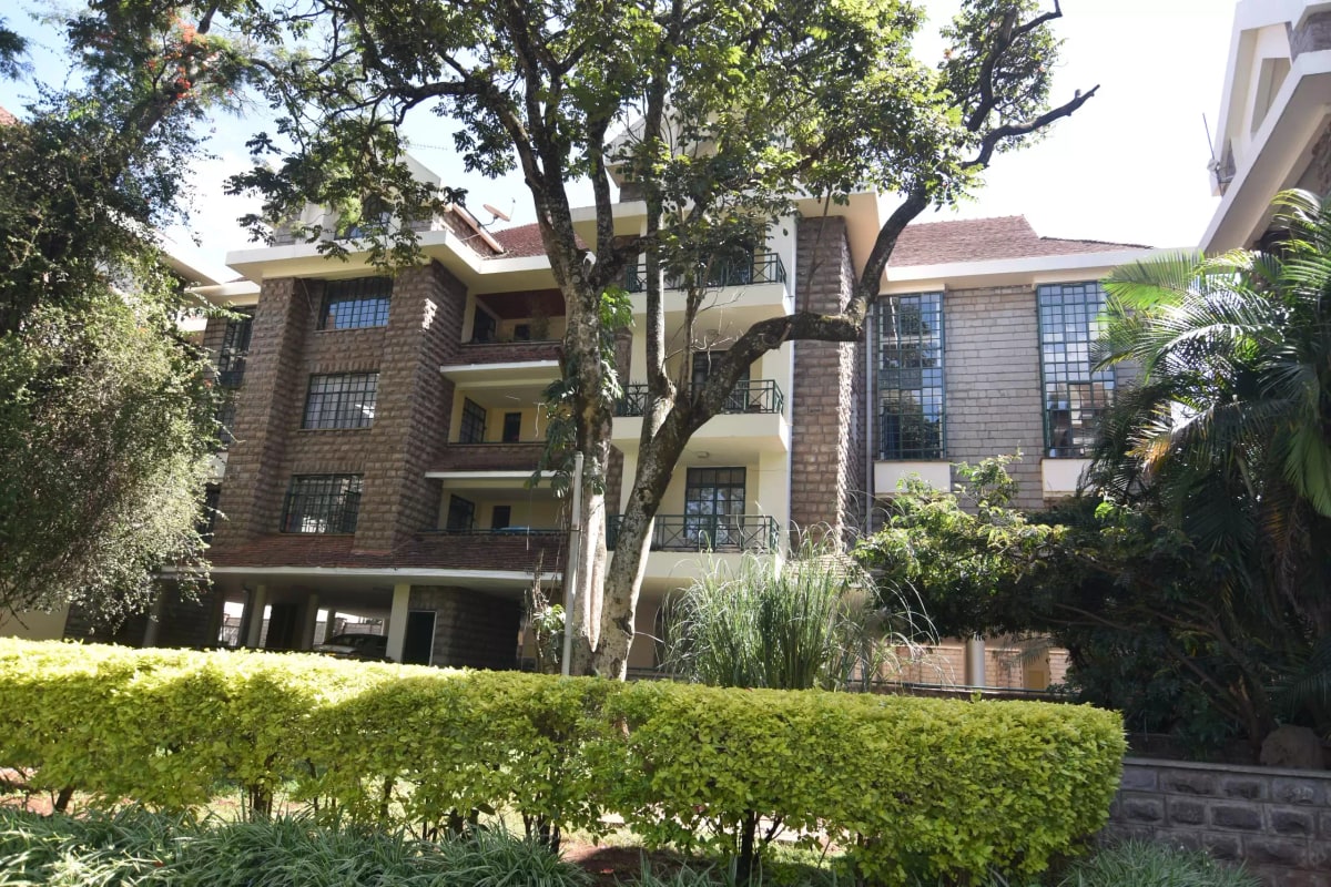 Multi-story brick residential building with mature landscaping