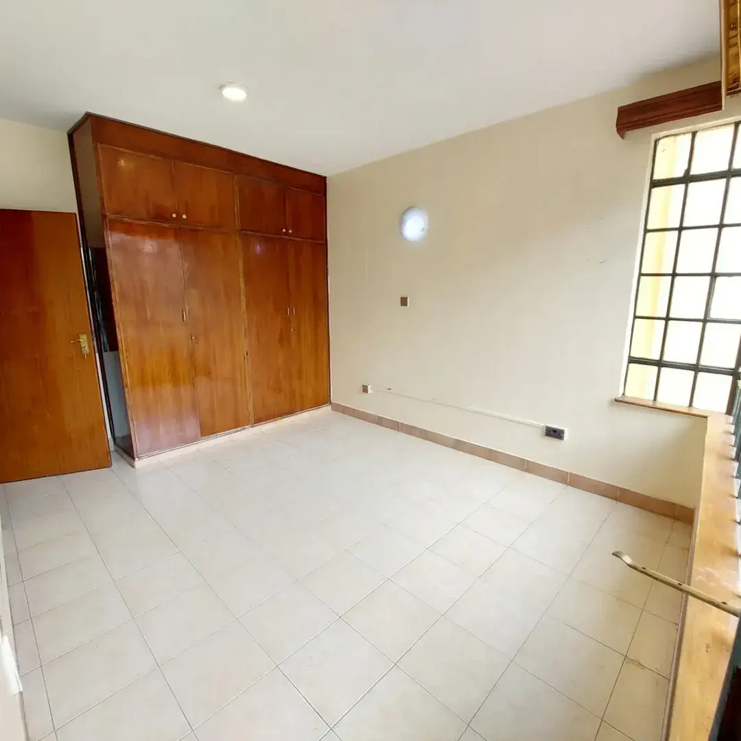 Spacious bedroom with wooden built-in wardrobes and natural light