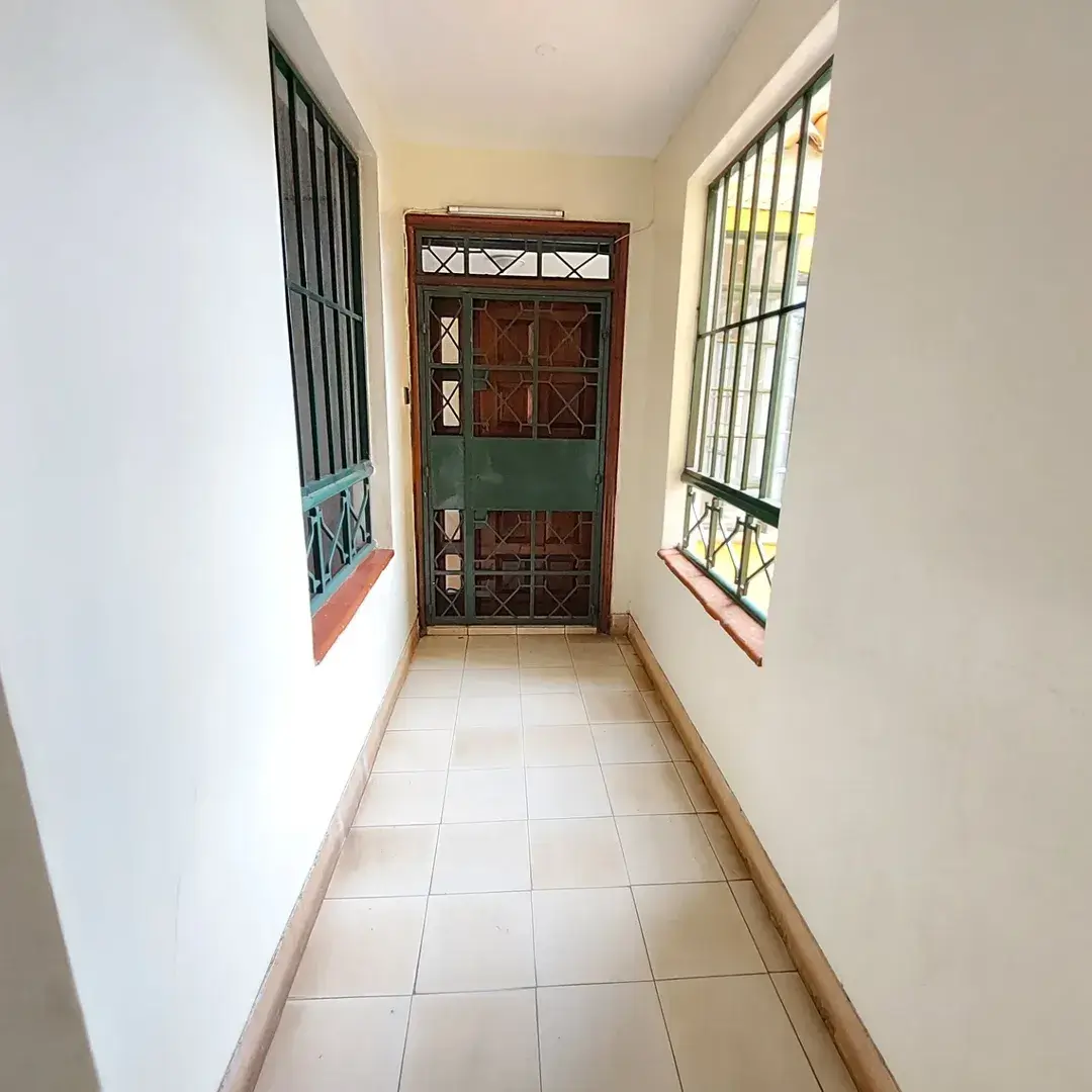 Narrow corridor with barred windows and wooden security door