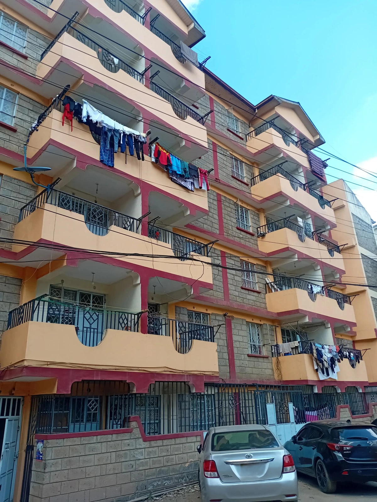 Multi-story residential building facade with balconies and street parking