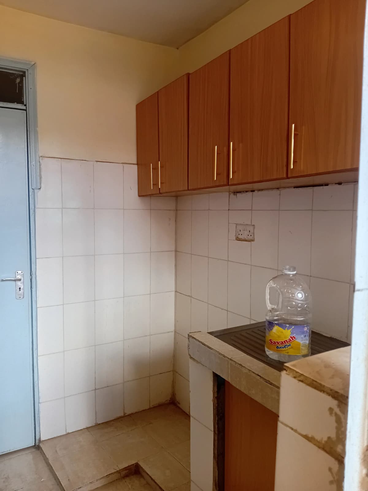 Compact kitchen with wooden cabinets and white tile backsplash