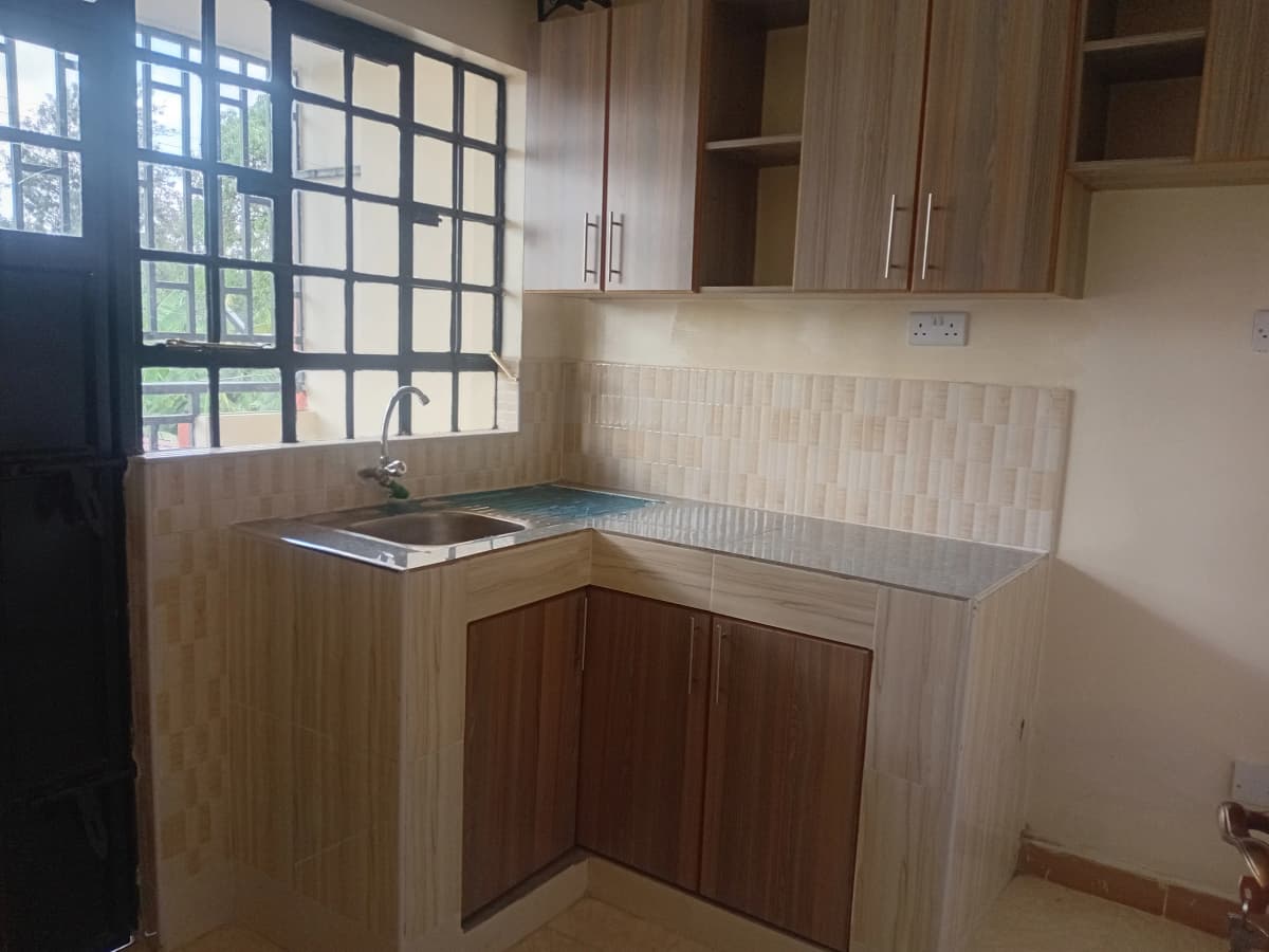 Compact L-shaped kitchen with stainless steel sink and upper cabinets
