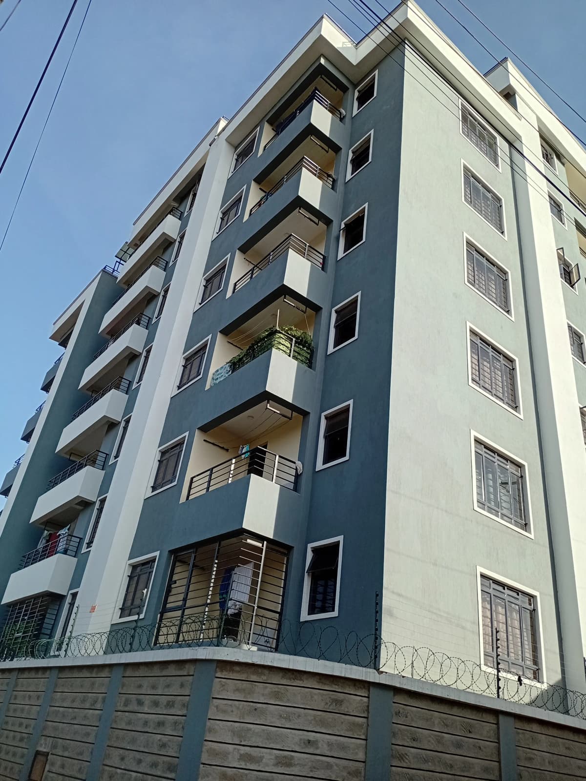 Modern multi-story residential building with balconies and metal fence