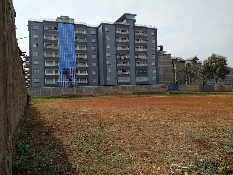 Multi-story residential building with compound grounds and red soil