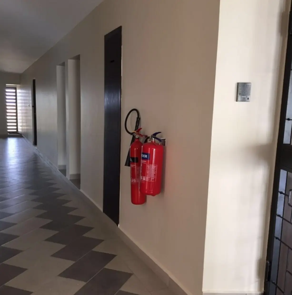 Building corridor with fire extinguishers and geometric floor tiles