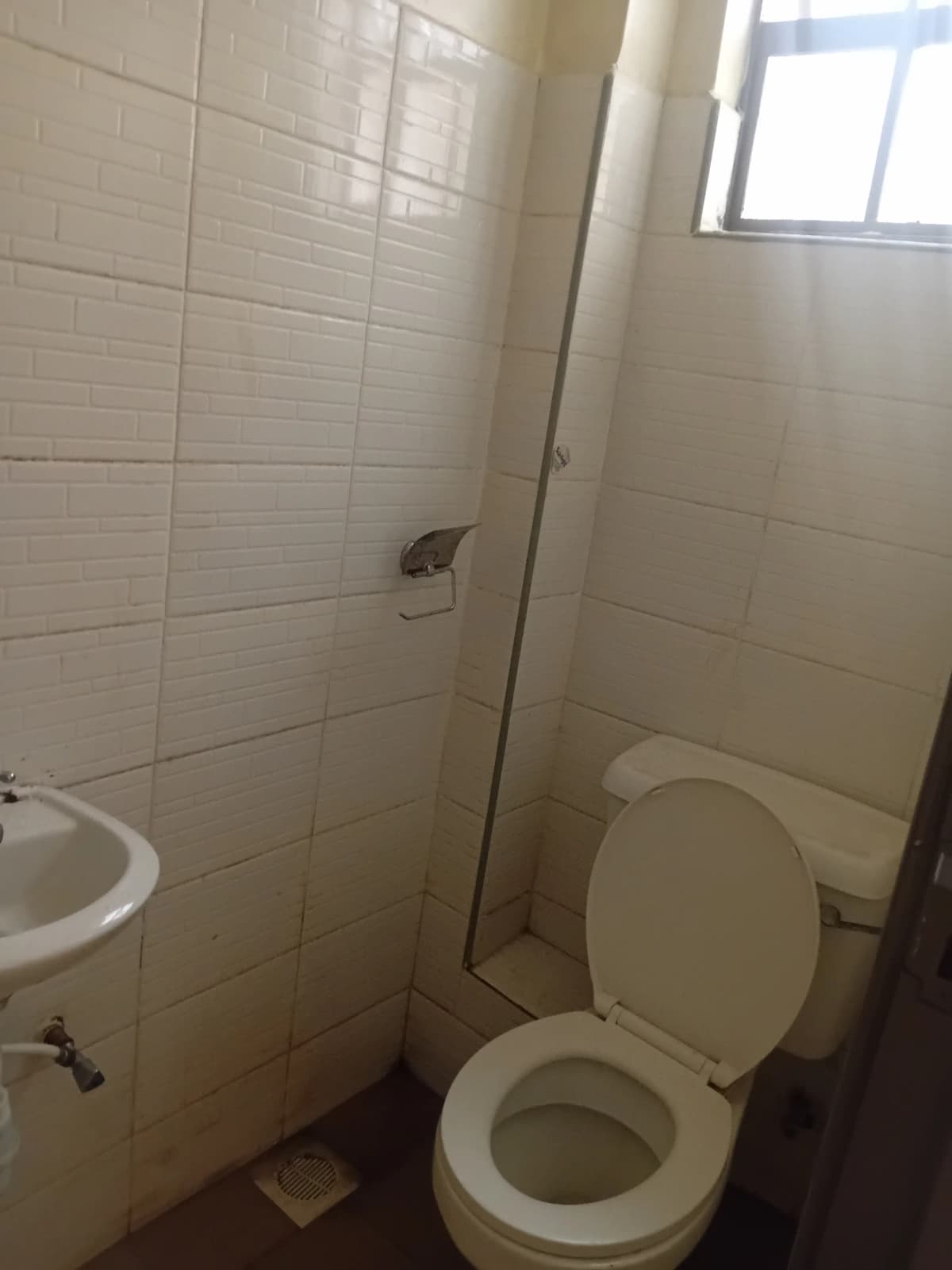 Basic bathroom with toilet, sink, and tiled shower enclosure