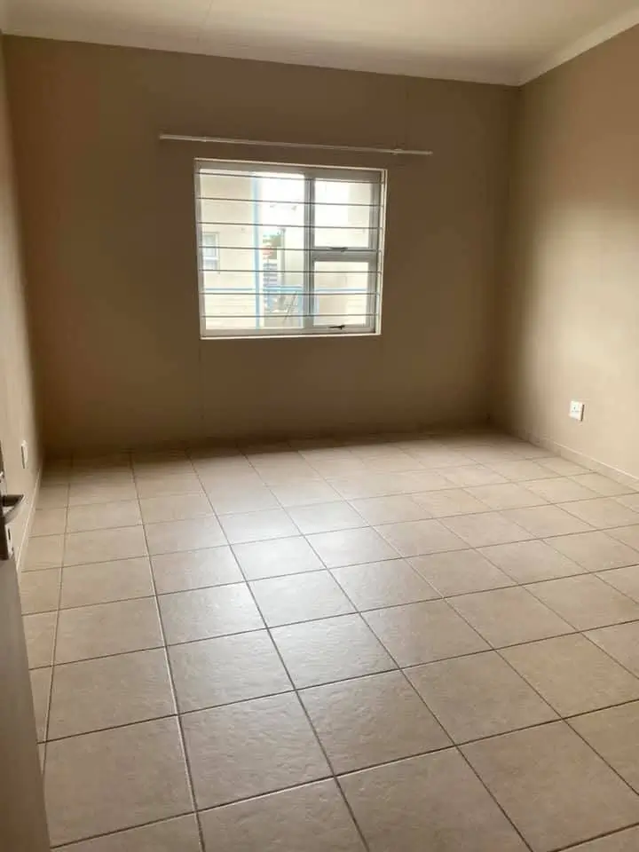 Empty bedroom with tiled floor and barred window