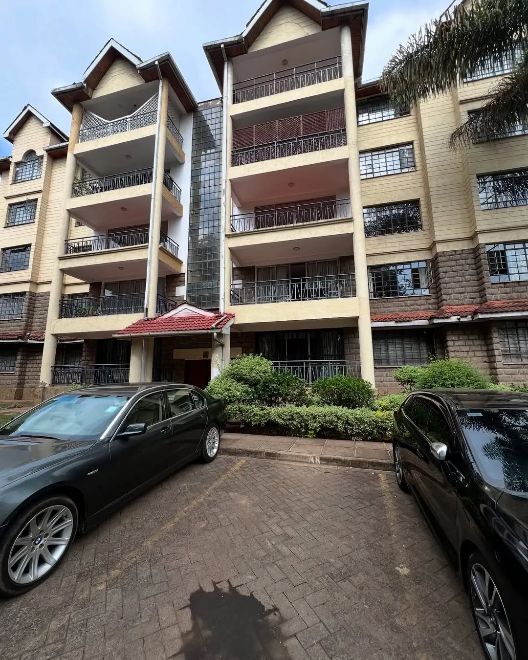Multi-story residential building with paved parking compound and vehicles