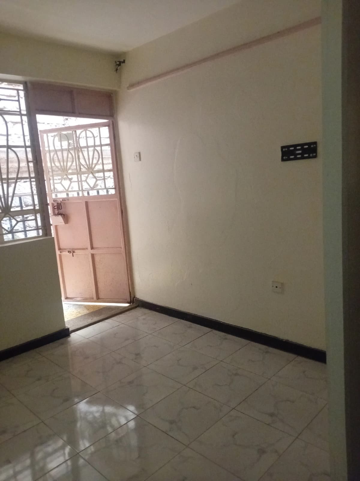 Compact entry hallway with tiled flooring and security gate door