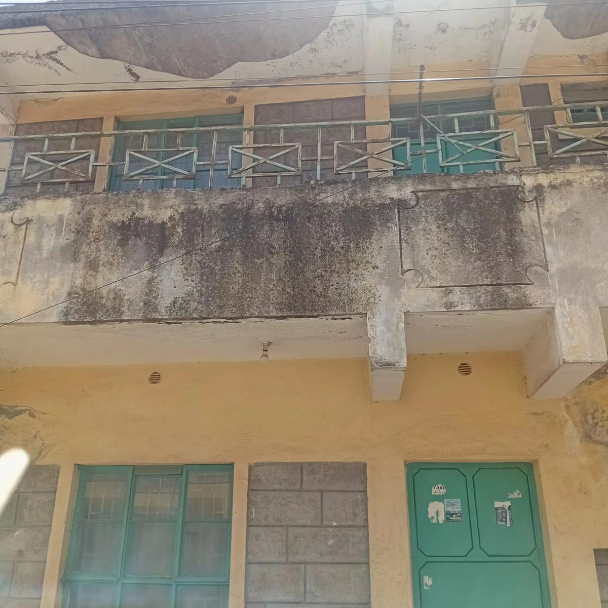 Weathered building facade with green doors and balcony railings