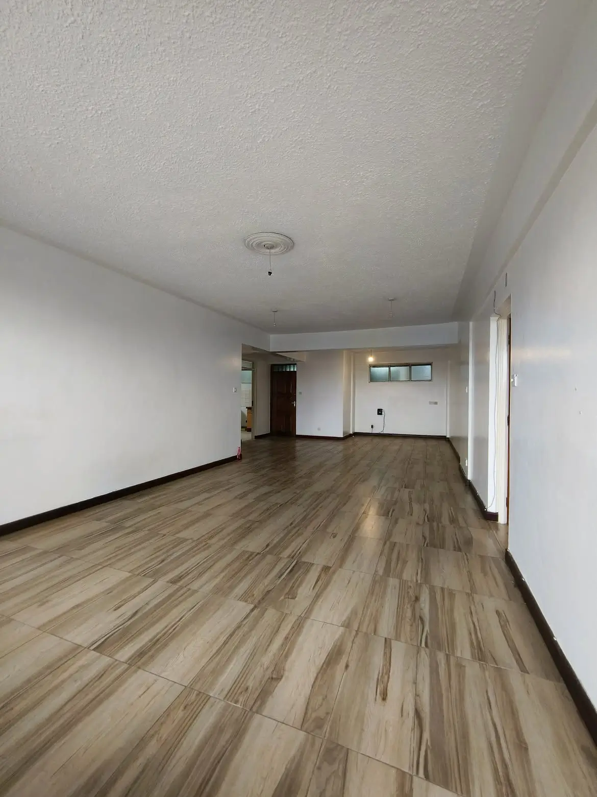Empty open-plan living room with wood-effect tile floor