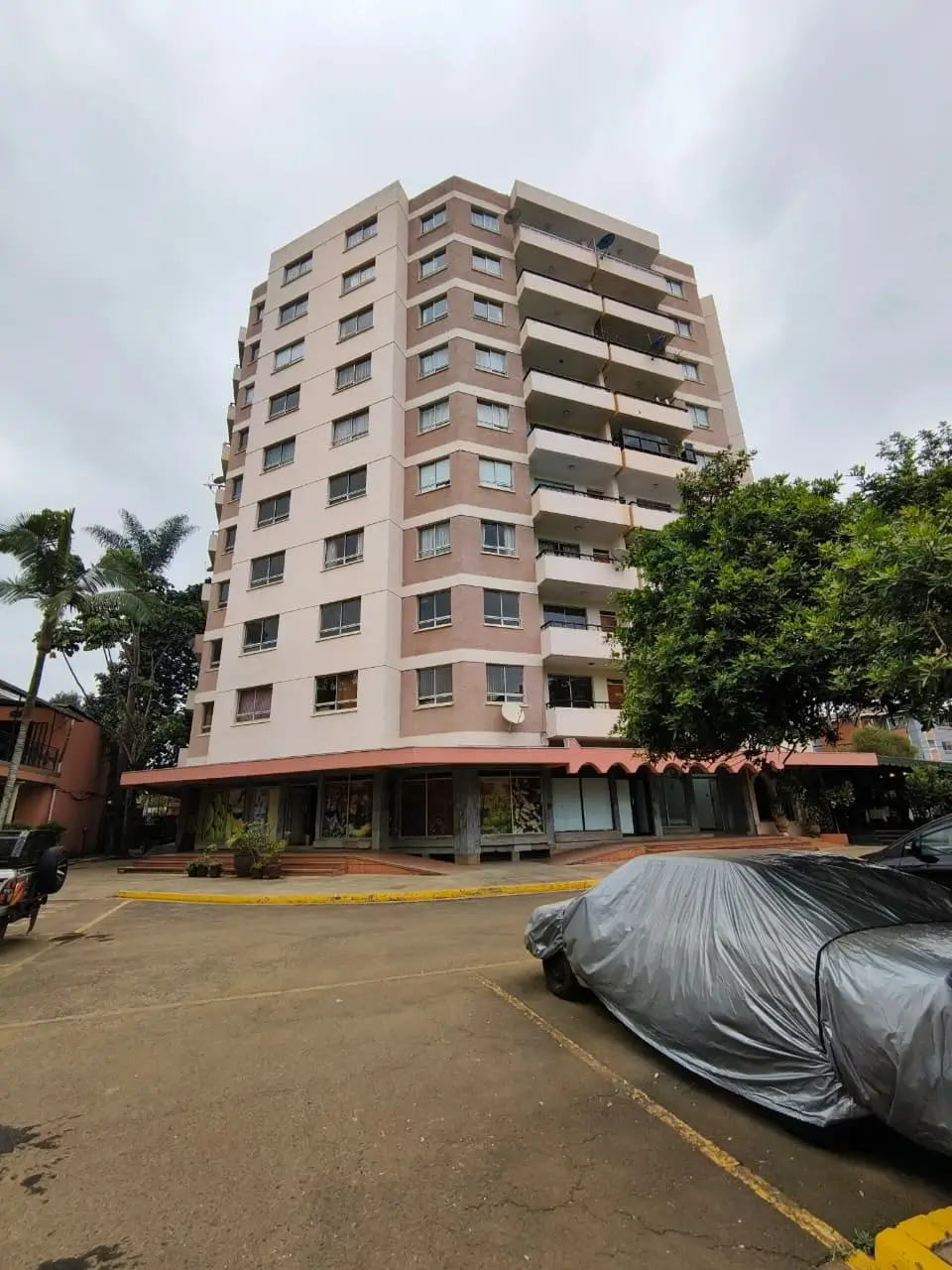 Tall multi-storey apartment block with foreground parking area