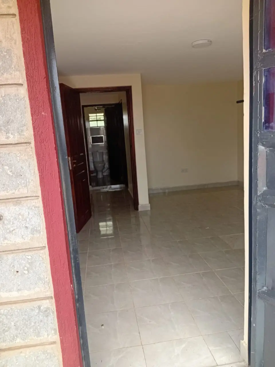 Empty hallway with tiled flooring and dark red door frame