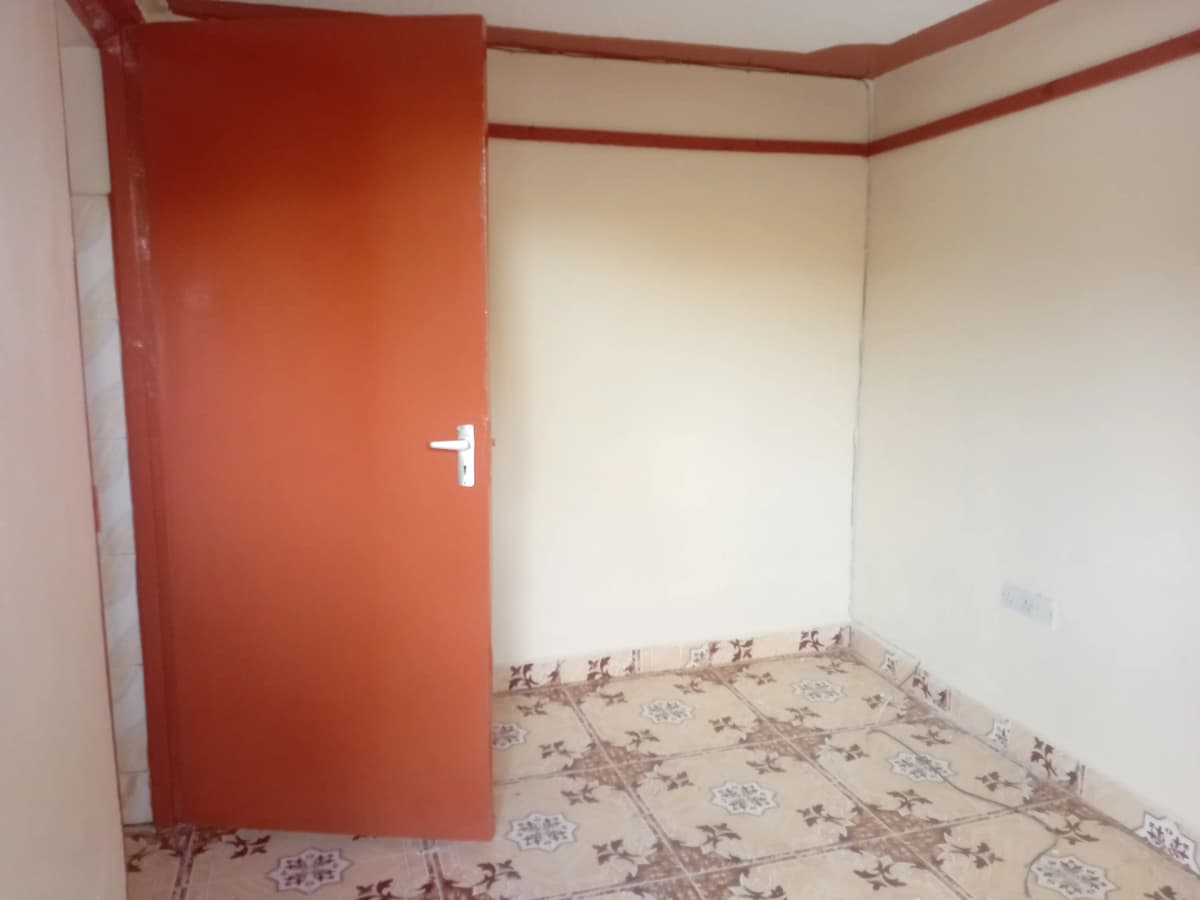 Empty bedroom with red accent door and patterned floor.