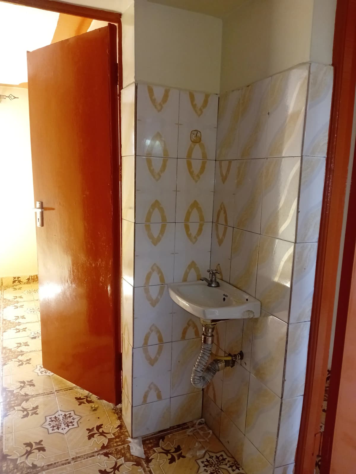 Compact bathroom with wall-mounted sink and patterned tiles