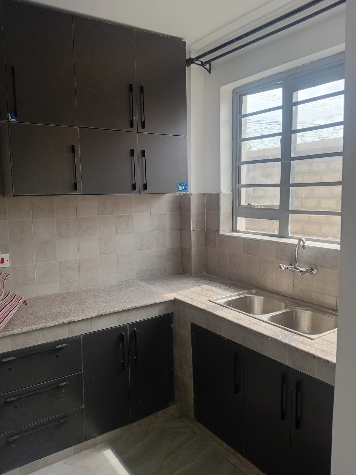 Compact modern kitchen with black cabinetry and stainless steel sink