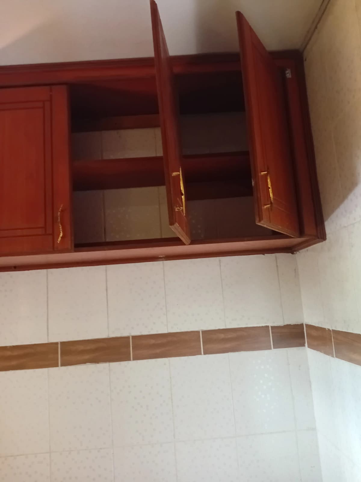 Red wooden wall cabinets with open doors, white tile backsplash