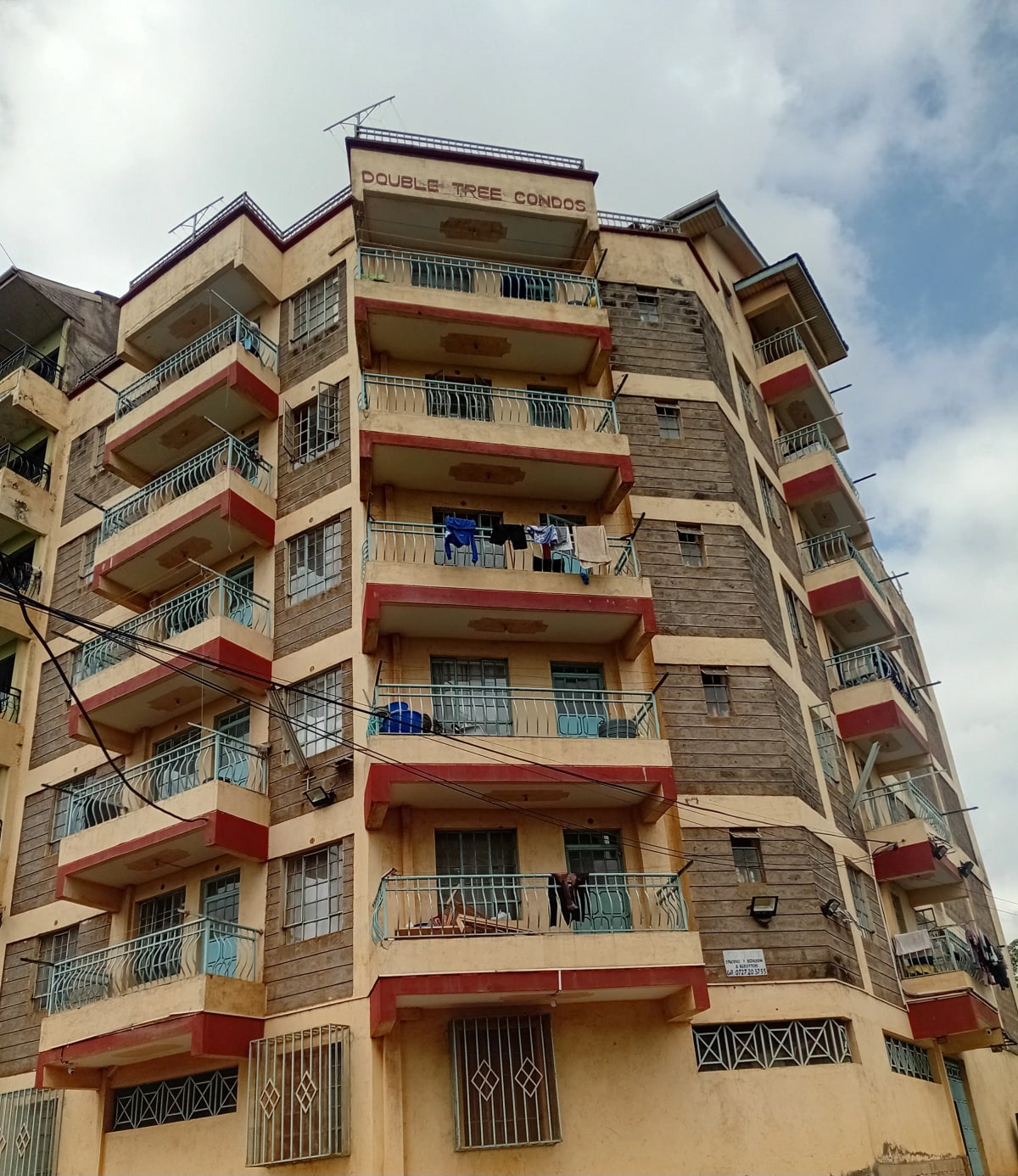 Multi-story residential building facade with balconies and red trim