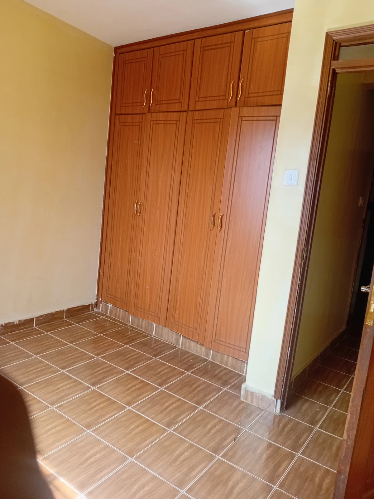 Spacious bedroom with built-in wooden wardrobes and tiled flooring