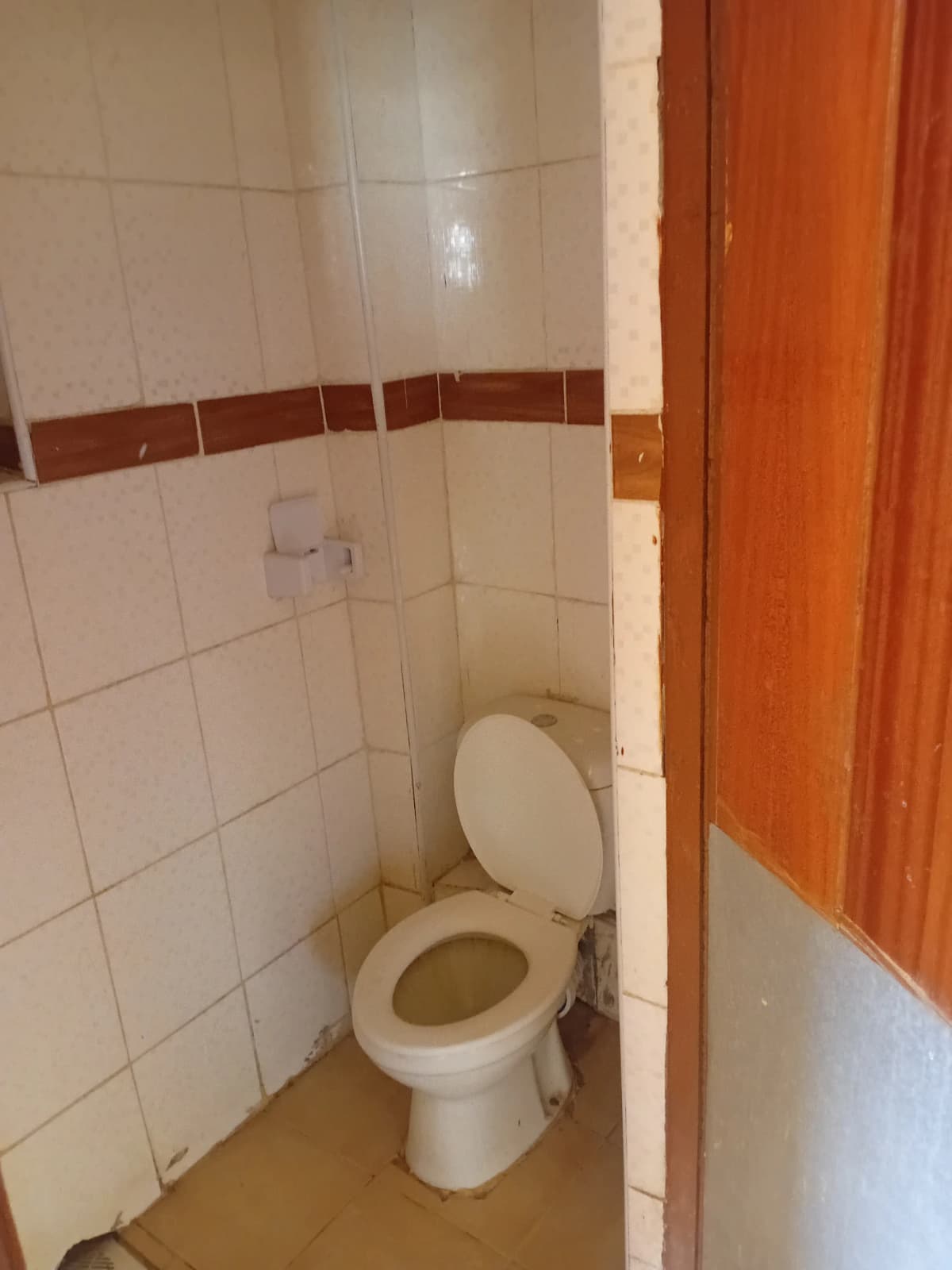 Compact bathroom with white tile walls and ceramic toilet