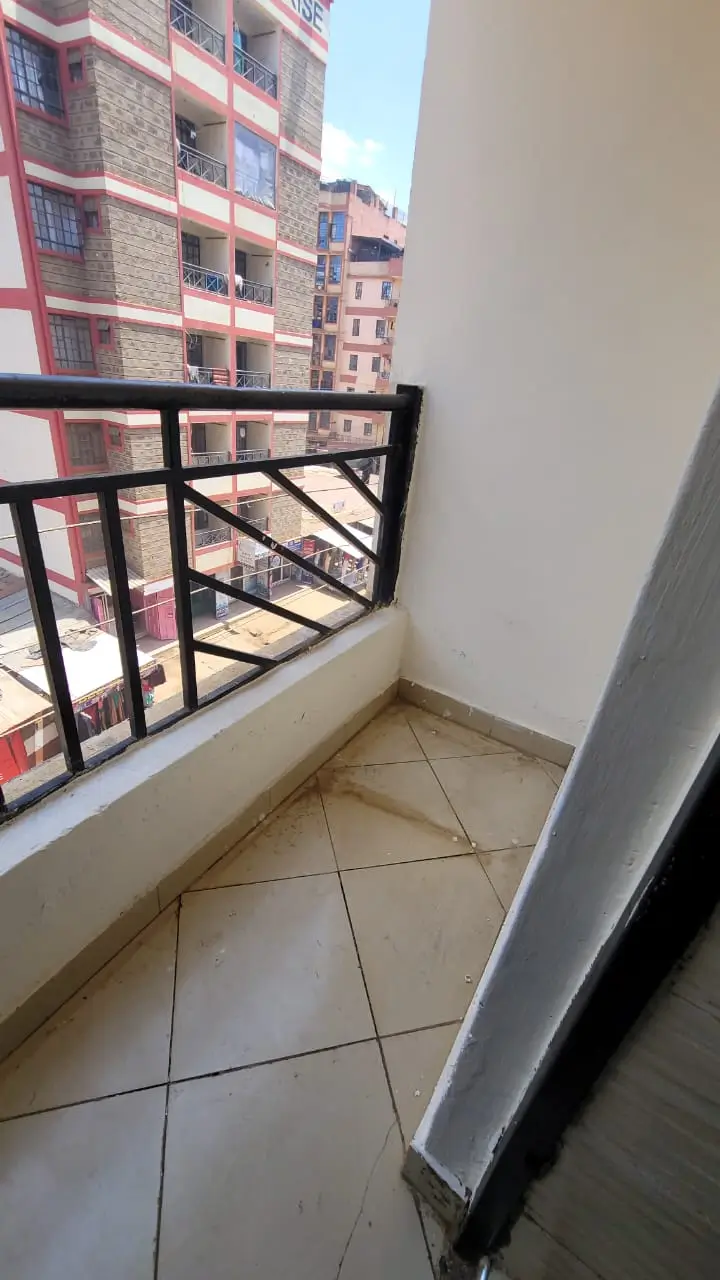 Small balcony with black railing overlooking residential buildings