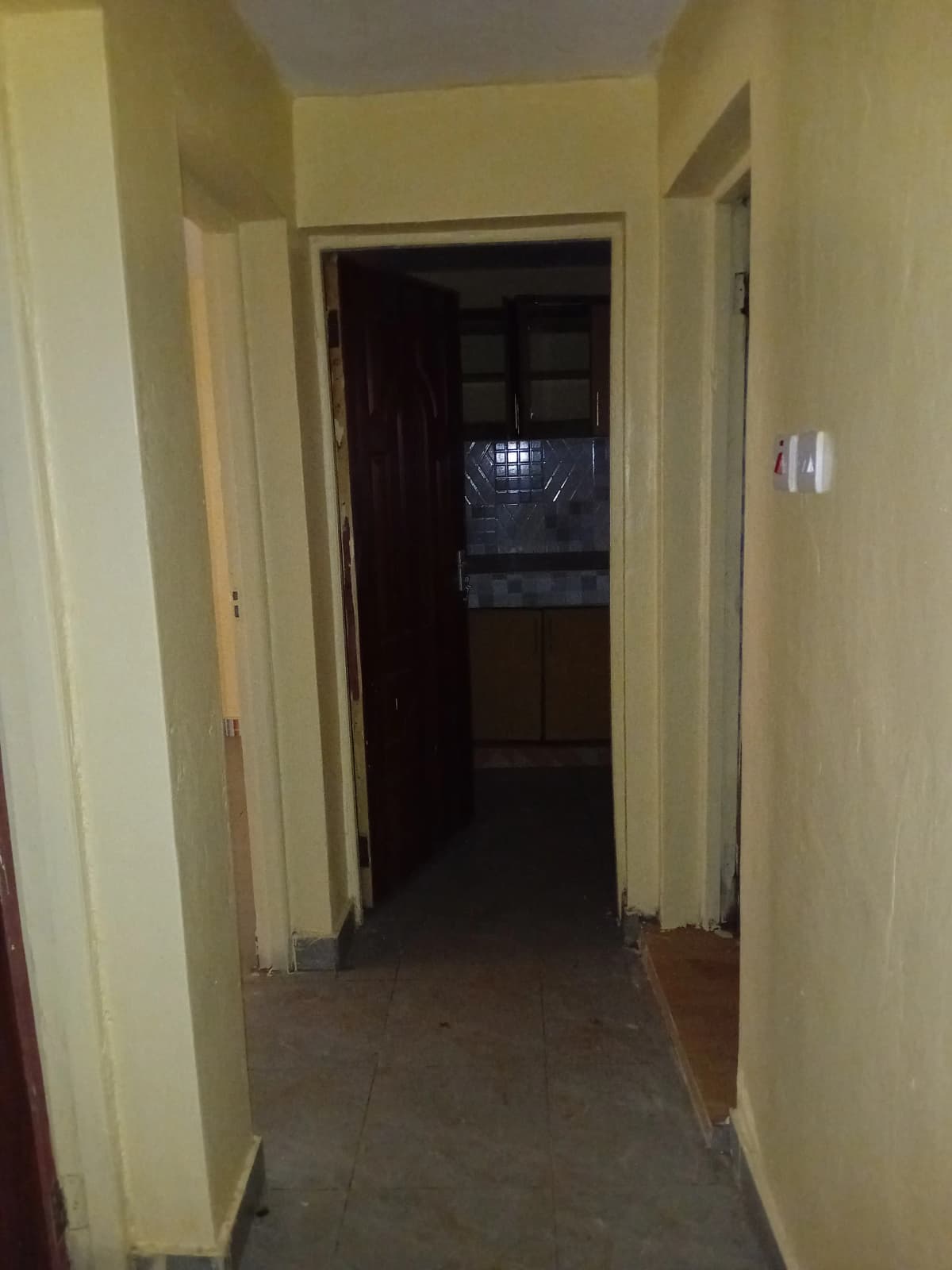 Narrow hallway with beige walls and dark flooring