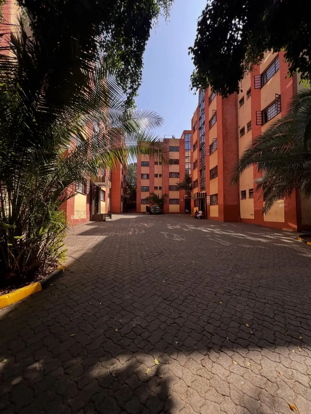 Red brick residential compound with paved driveway and landscaping