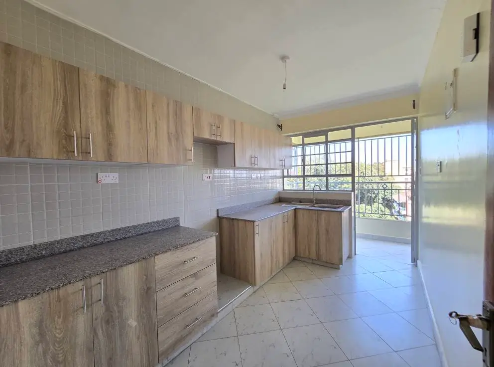 Modern kitchen with wood cabinets, dark countertops, balcony access