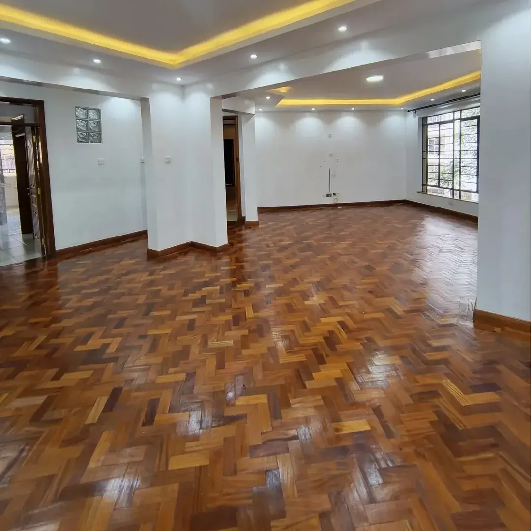 Spacious empty living room with herringbone parquet flooring.