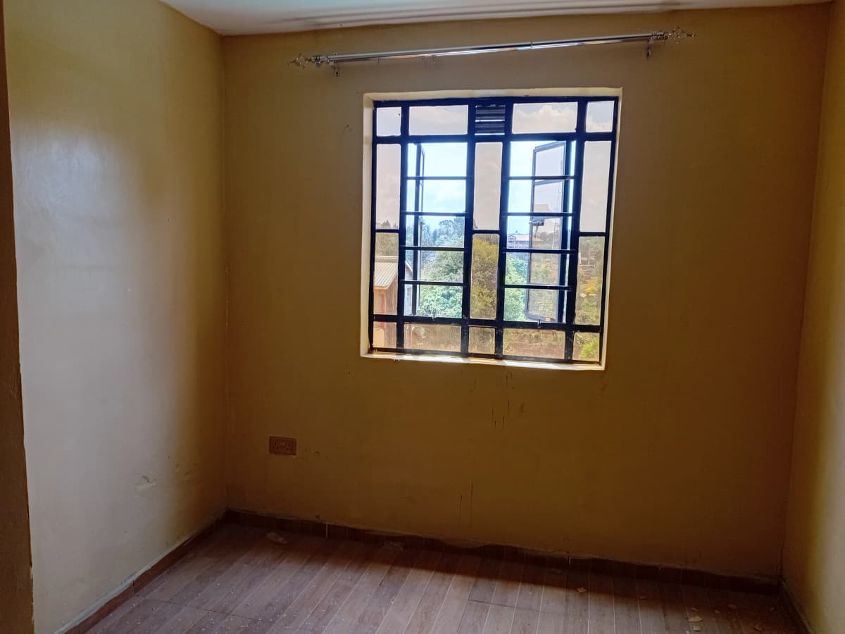 Unfurnished bedroom with barred window and ochre walls