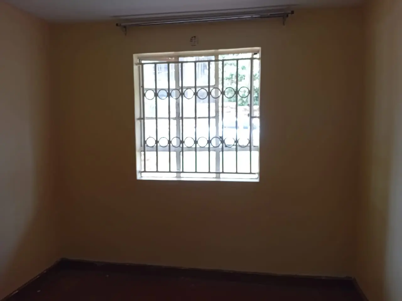 Empty bedroom with barred window and warm-toned walls