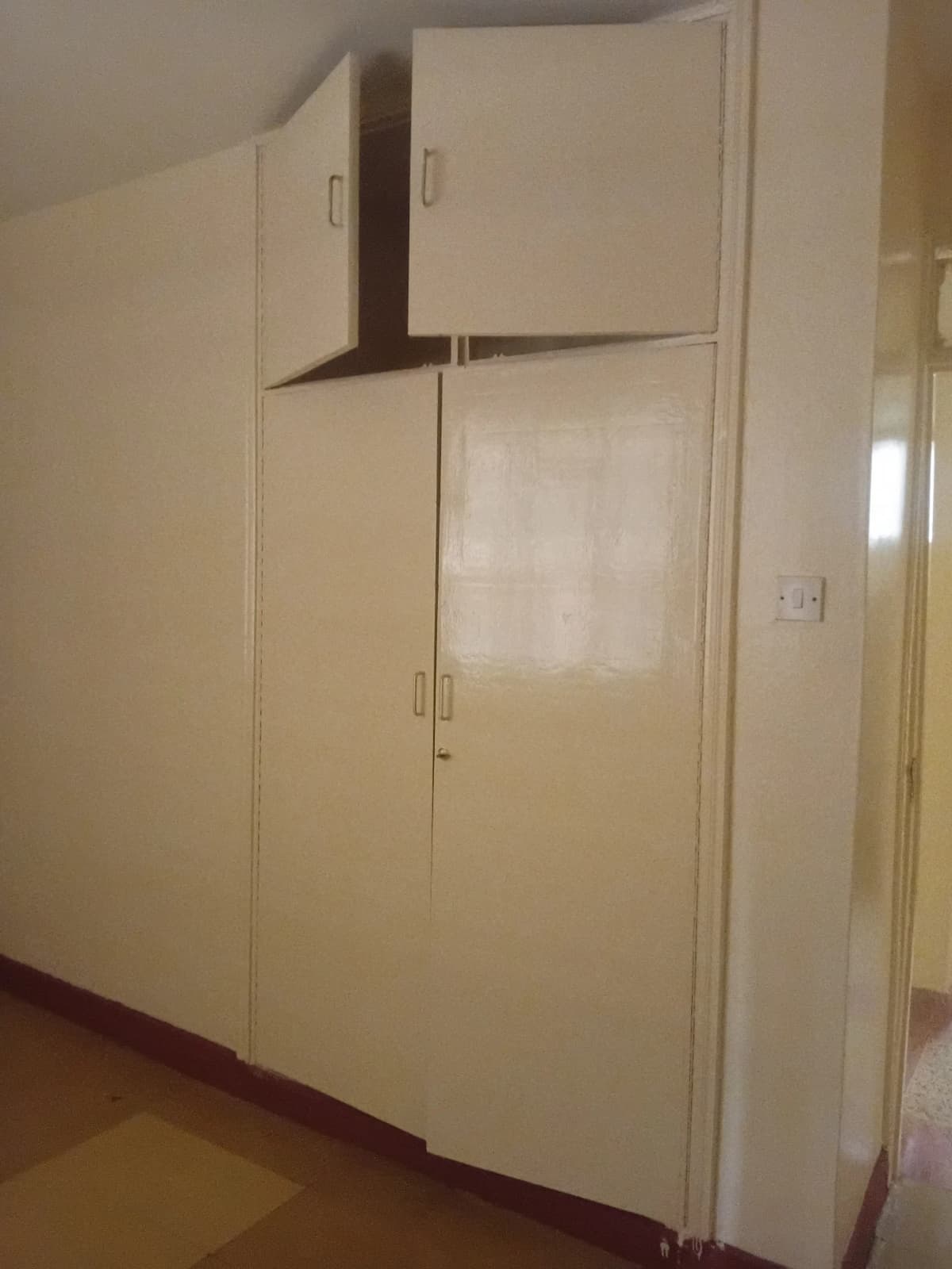 Compact kitchen with cream cabinetry and built-in appliances
