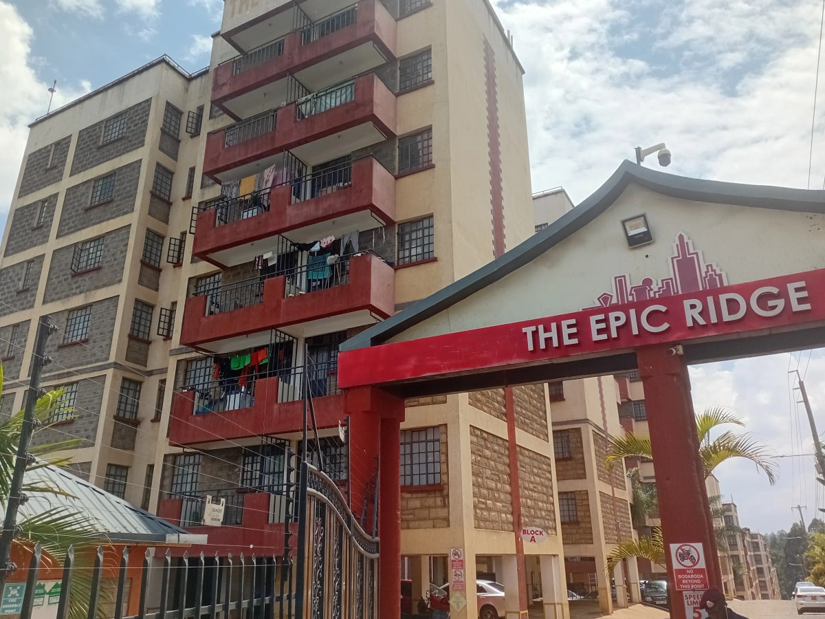 Multi-story residential building with red balconies and gate entrance